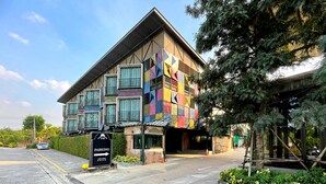 A multi-story building with a colorful facade, a visible entrance, and a parking sign indicating availability. - Nights in a Box (Chonburi)