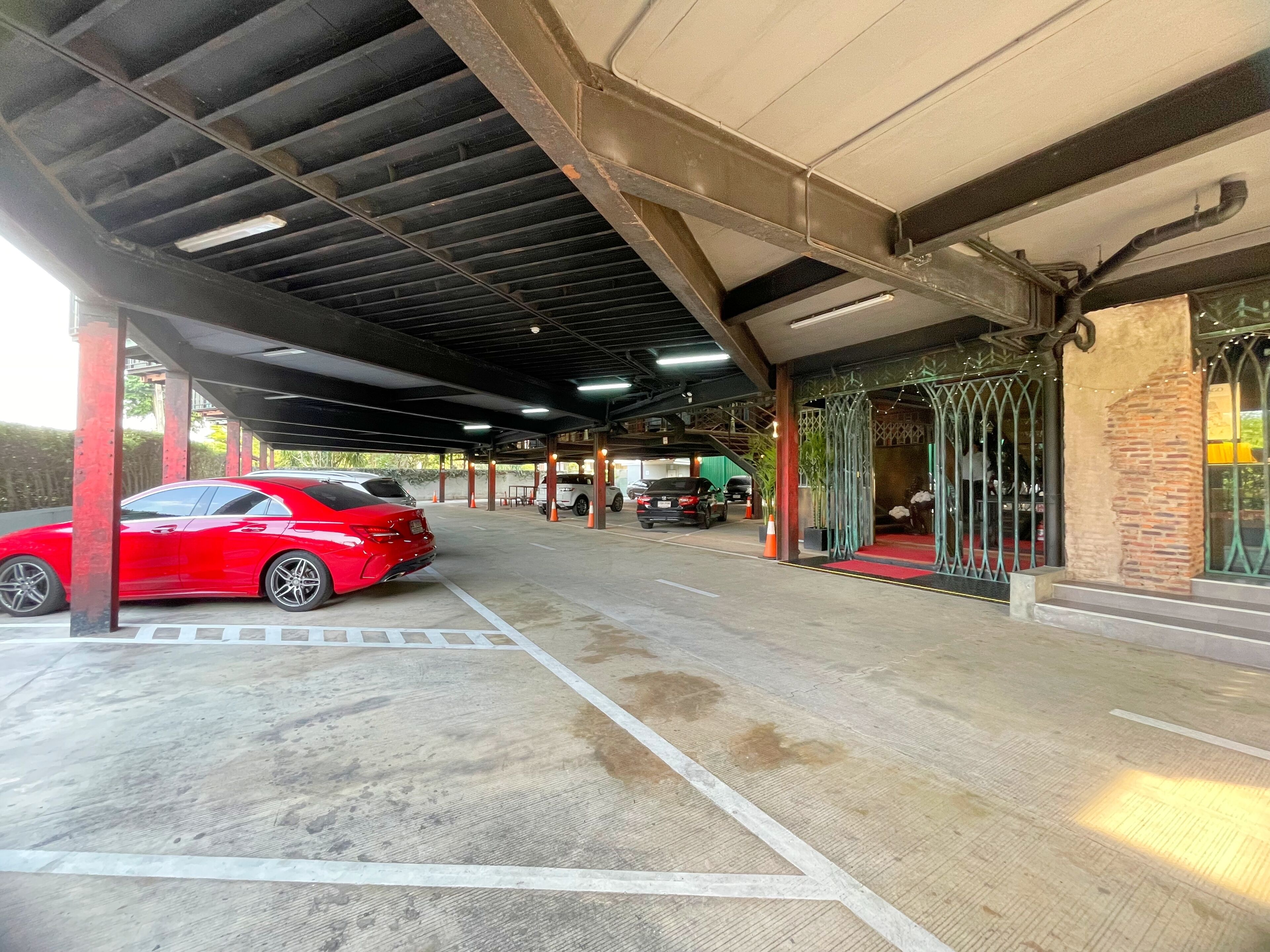 Un espace de stationnement couvert où une voiture rouge est garée dans un emplacement prévu à cet effet.