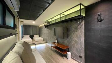 Un dormitorio moderno y funcional con una litera, una pequeña zona de estar y un espejo grande en la pared.