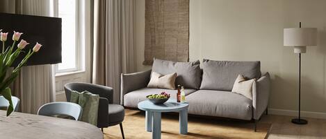 Relax in this stylish living room with a grey sofa, round coffee table, and large flat-screen TV.