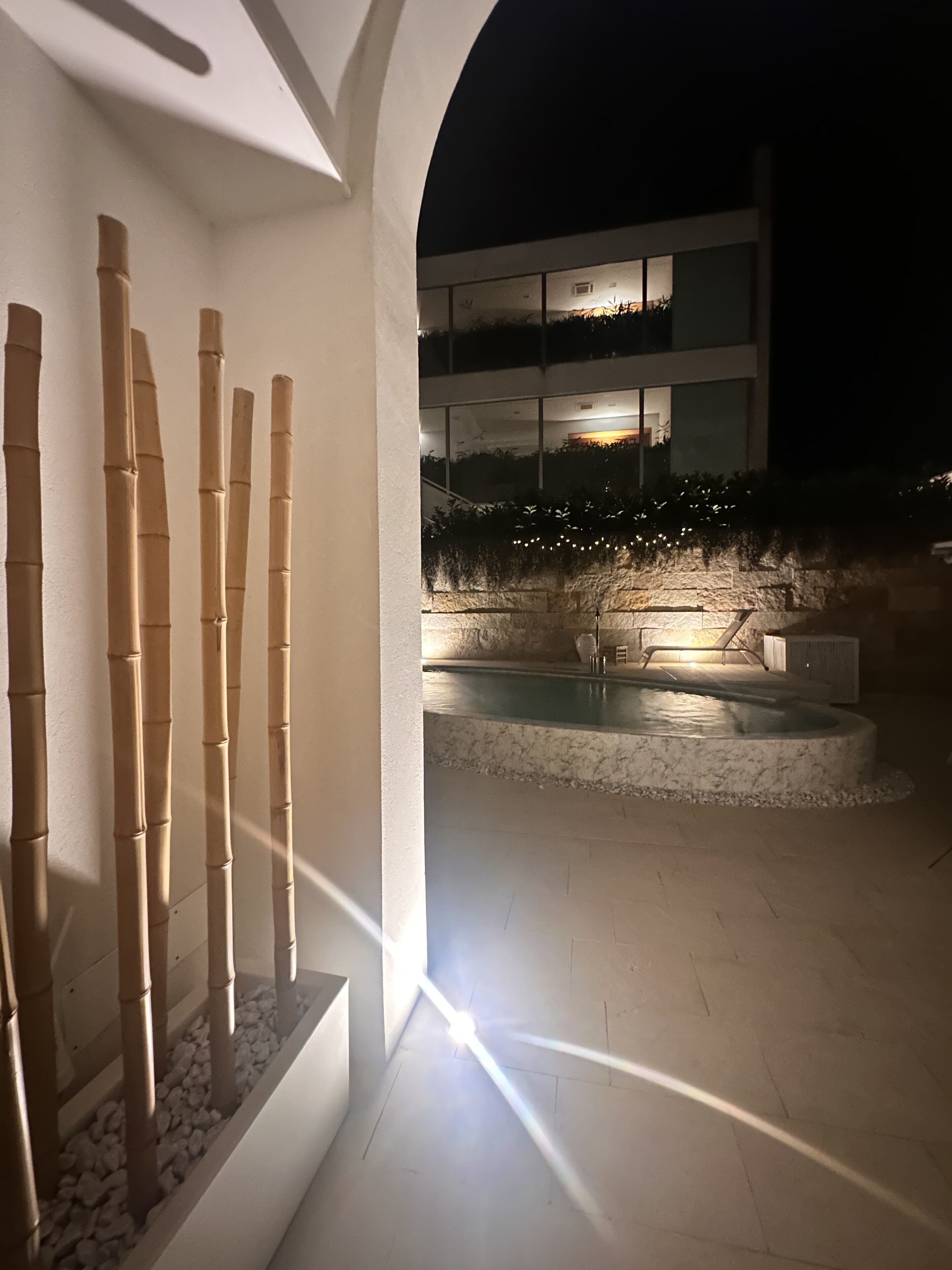 Een modern gebouw met een zwembadgedeelte, bamboe decoratie en een pad van stenen.
