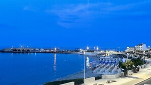 Eine Uferpromenade mit einem Hafen, Booten und einer Reihe von blau-weißen Gebäuden am Ufer.