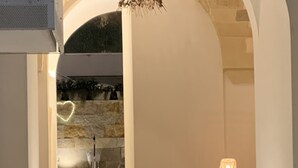 Ein gemütlicher Sitzbereich mit gepolsterten Bänken und einer Couch, einer Steinsäule und einer hängenden Lampe.