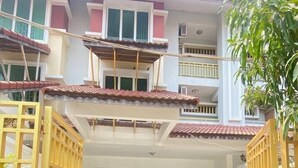 Um edifício de vários andares com portão, plantas em vasos e área coberta com telhado de azulejos.