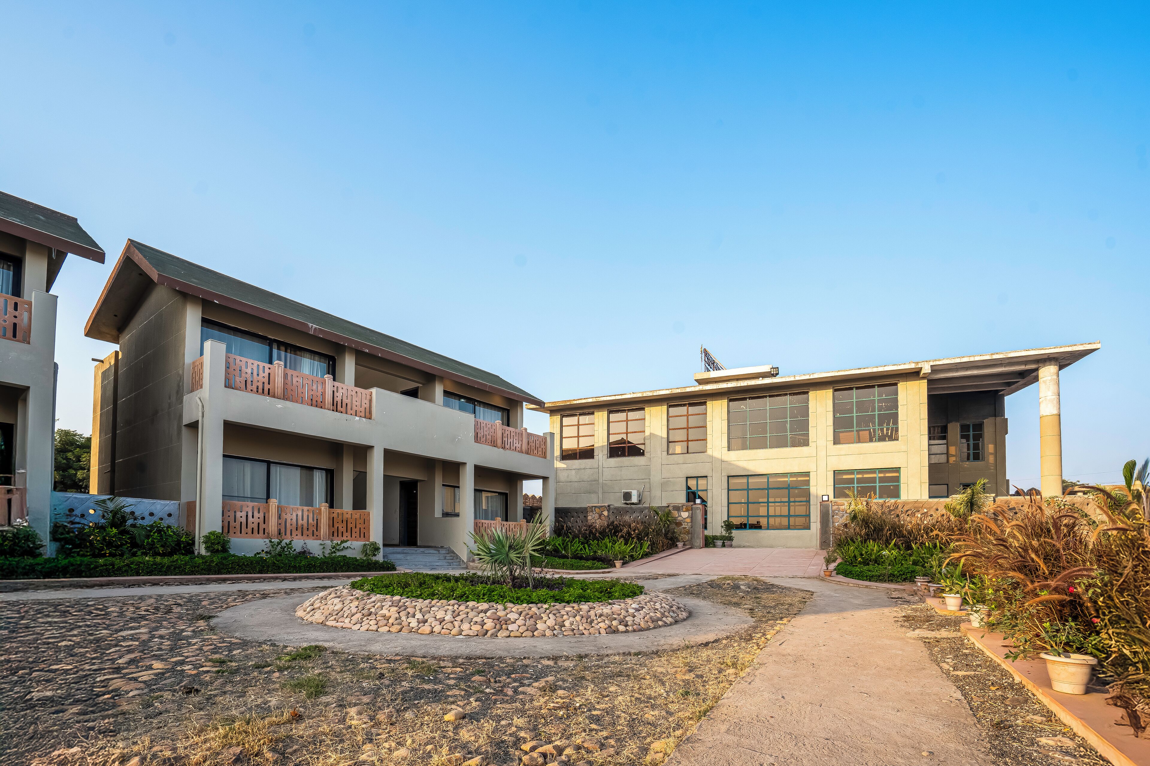 A modern building with multiple floors, a central courtyard with a stone pathway, and surrounding greenery.