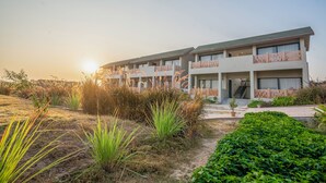 A modern hotel with multiple balconies, a well-maintained garden, and a clear view of the sunset. - Jay Gurudev Palpur Fort Kuno By Paandora Collections (Karahal)