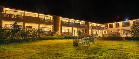A hotel with multiple floors, outdoor seating area, and well-lit entrance.