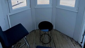 Habitació amb vista a la platja, una cadira i una taula petita.