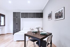 Une chambre à coucher moderne comprenant un lit, une petite table à manger avec des chaises et une armoire à plusieurs compartiments.