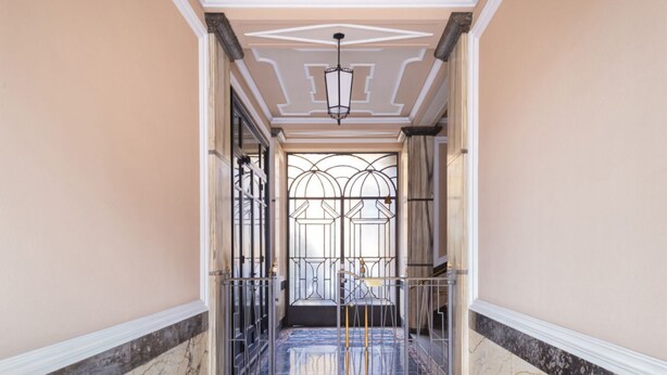 A hallway with a marble floor, a metal gate, and a decorative ceiling. - Easylife - Studio with balcony in Risorgimento (Milano)