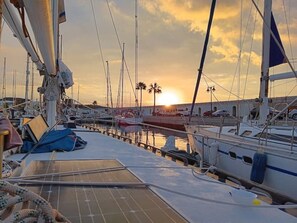 Un port de plaisance avec des bateaux amarrés, un coucher de soleil en arrière-plan et un ciel dégagé.