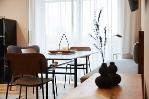 Un salon moderne avec une table à manger, des chaises et un canapé. On peut voir un vase orné d’objets décoratifs sur la table.