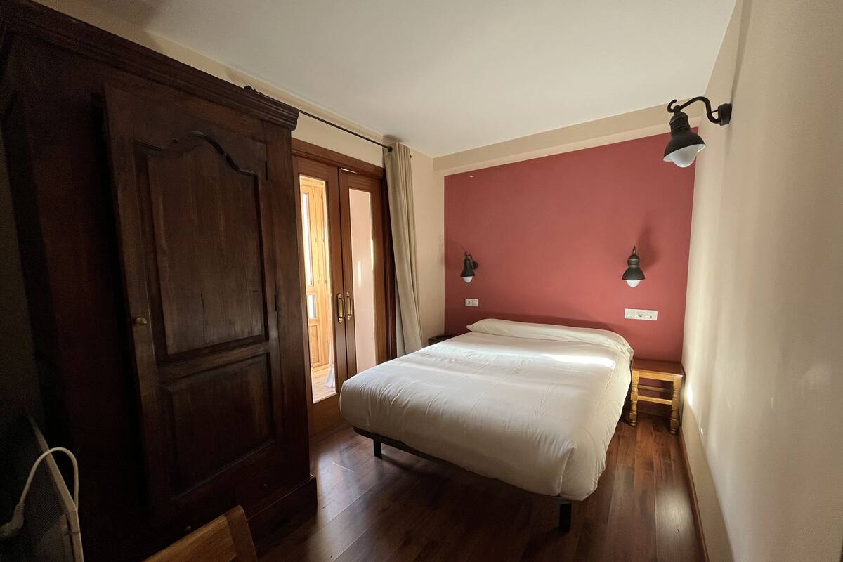 Un dormitorio con una cama, un armario de madera y dos lámparas de pared.