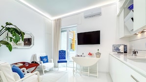 Une chambre d’hôtel moderne aux couleurs claires, dotée d’un téléviseur à écran plat, d’un coin repas et d’une grande fenêtre.