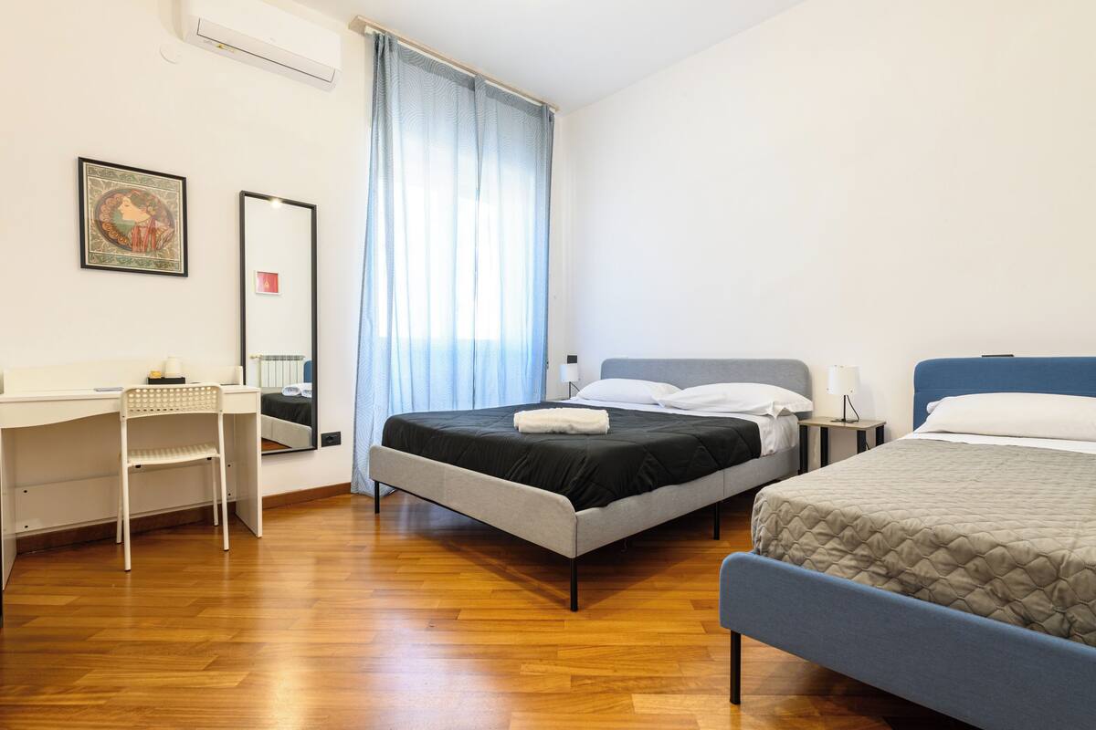 A bedroom with a bed, a desk, a chair, and a mirror.