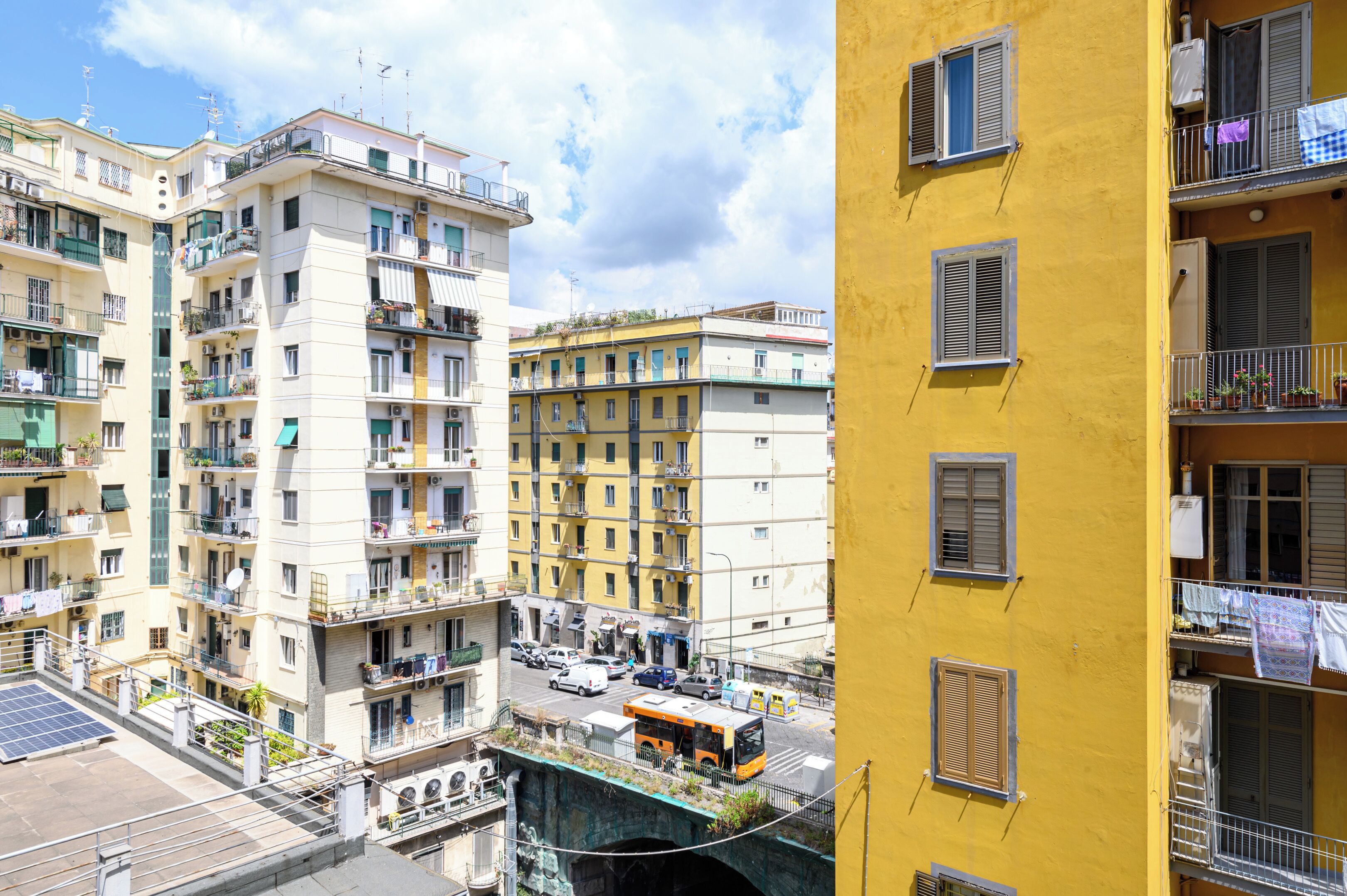 Un immeuble résidentiel à plusieurs étages, doté de balcons, donnant sur la rue et surmonté d’un pont.