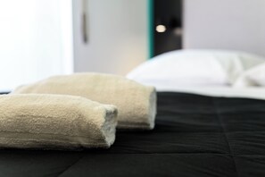 A neatly made bed with a black bedspread and two folded towels. - Dimora Vomero (Naples)