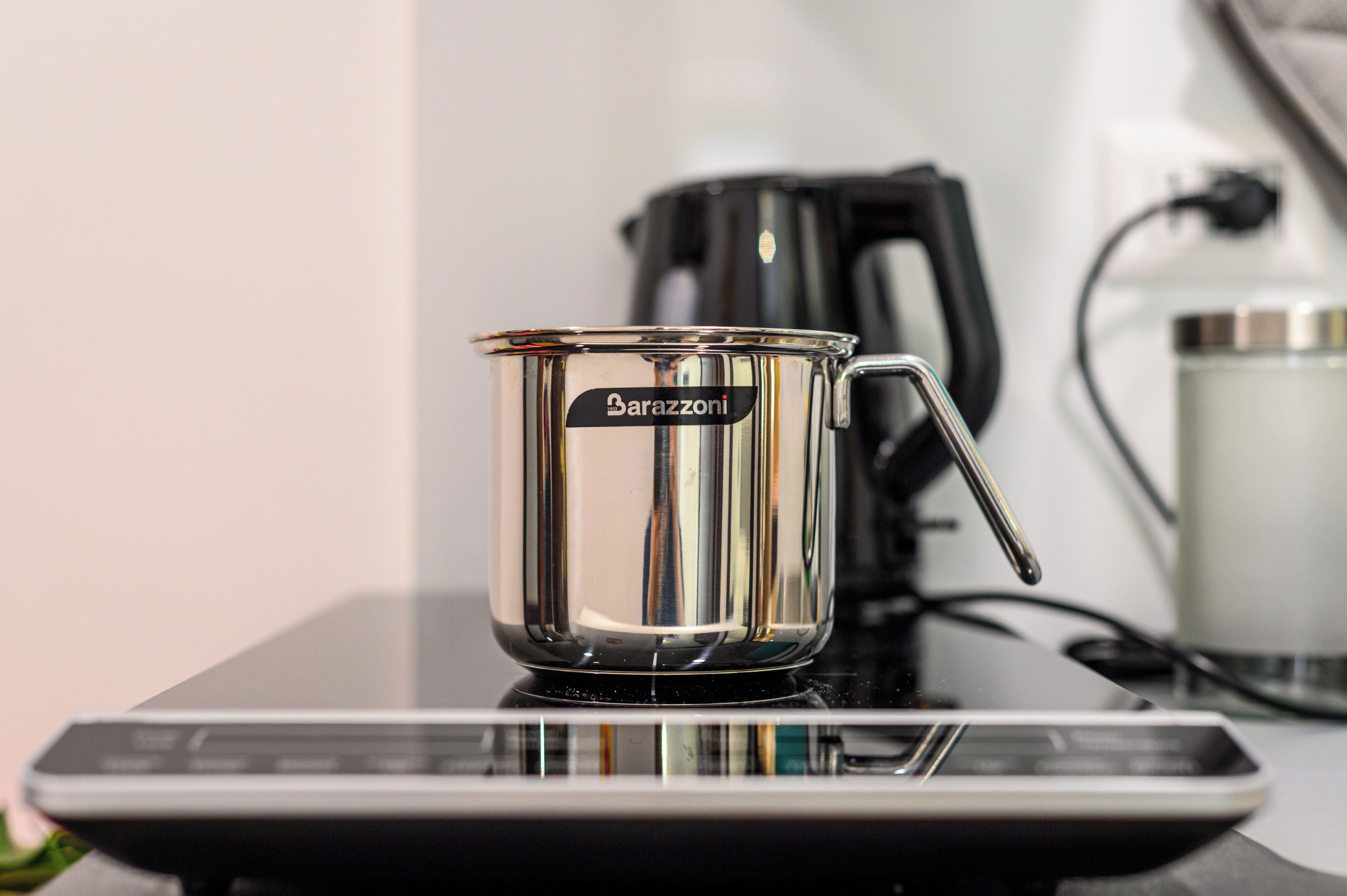 A clear glass coffee cup with a handle on a reflective surface, possibly a table or counter.