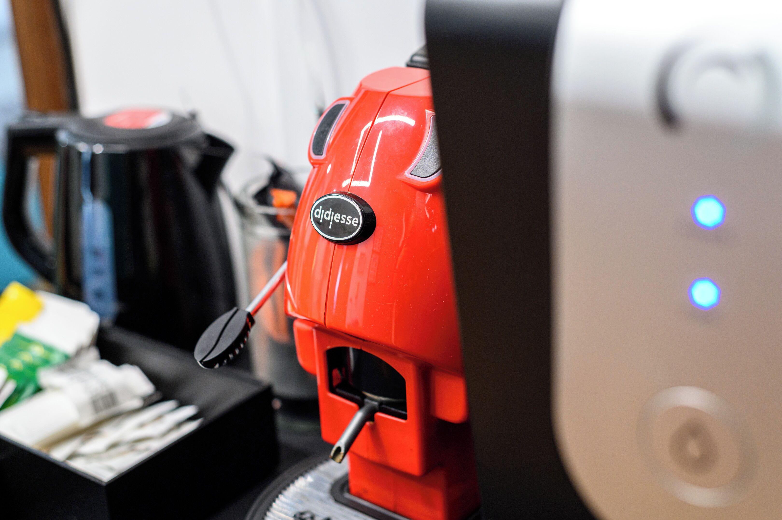 Una cafetera roja con panel de control negro y un depósito para cápsulas de café.