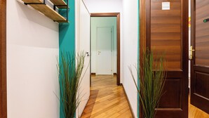 Un pasillo con suelo de madera, una escalera y dos plantas en macetas.