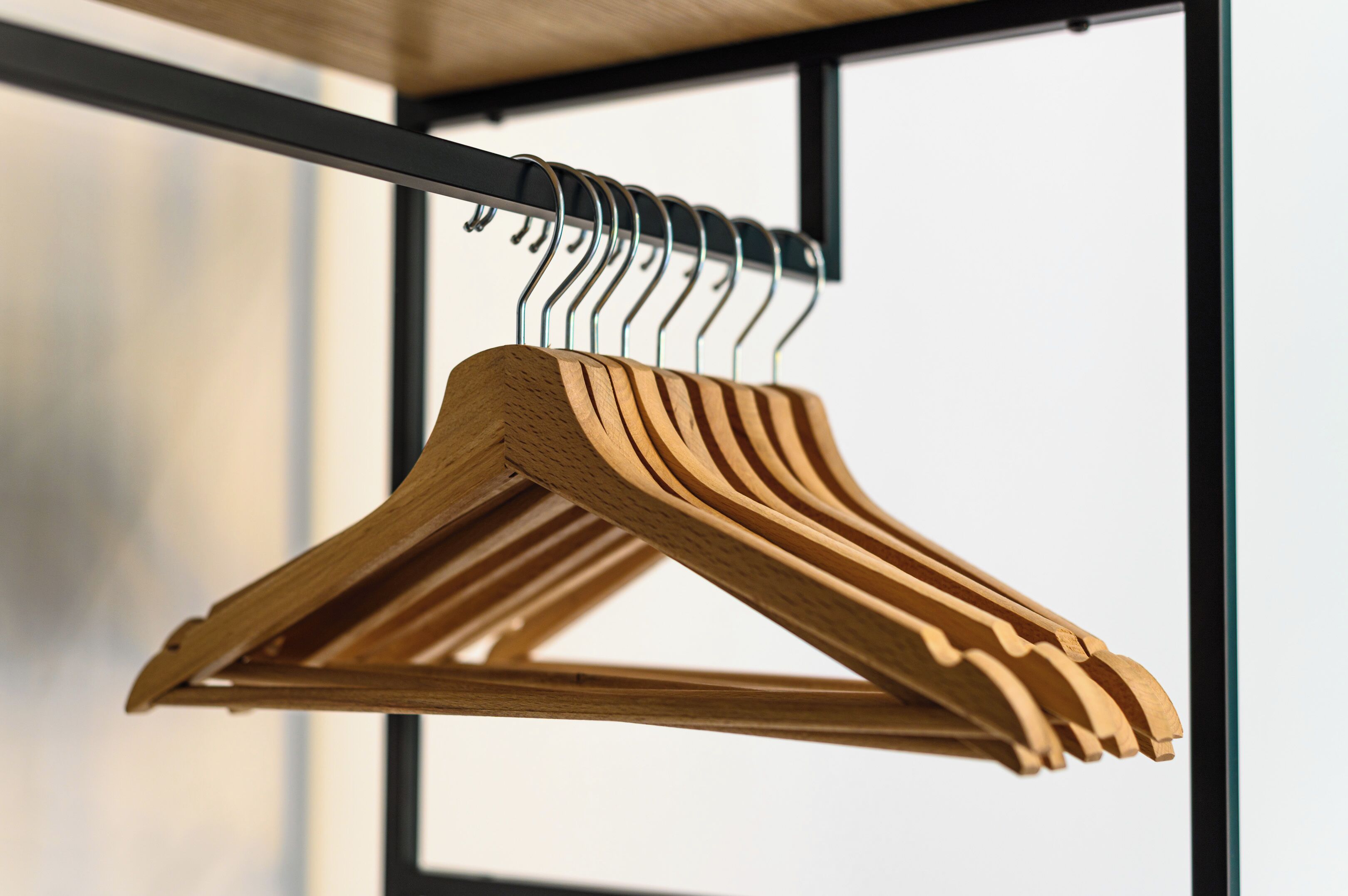 A wooden hanger rack with multiple hangers, mounted on a metal frame.