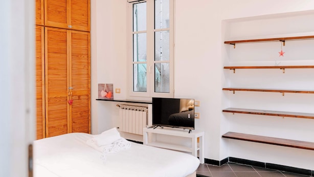 Ein Schlafzimmer mit Bett, Fernseher, Kleiderschrank und Fenster.