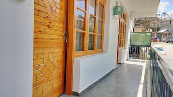 Un pasillo de hotel con puertas y ventanas de madera, un letrero verde y suelo de baldosas.