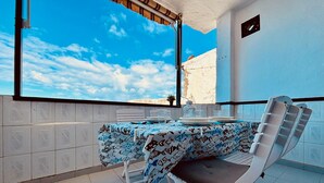 Een balkon met een eettafel, een stoel en uitzicht op de lucht.