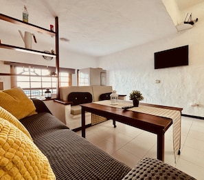 A modern living room with a sofa, a coffee table, and a TV mounted on the wall.