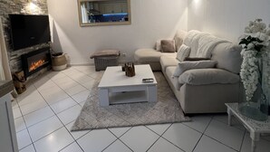 Una sala de estar moderna con chimenea, televisor, sofá y una mesa de centro.