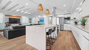 A modern kitchen with a central island, stainless steel appliances, and pendant lighting. - Beach Condo by Otium | Steps from Oceanpark Beach (San Juan)