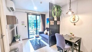 Un salon moderne comprenant un canapé, une table à manger, un téléviseur et une porte coulissante donnant sur un balcon.
