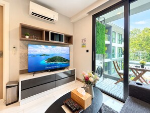 Un salon moderne avec un téléviseur à écran plat, une petite plante et un vase rempli de fleurs.