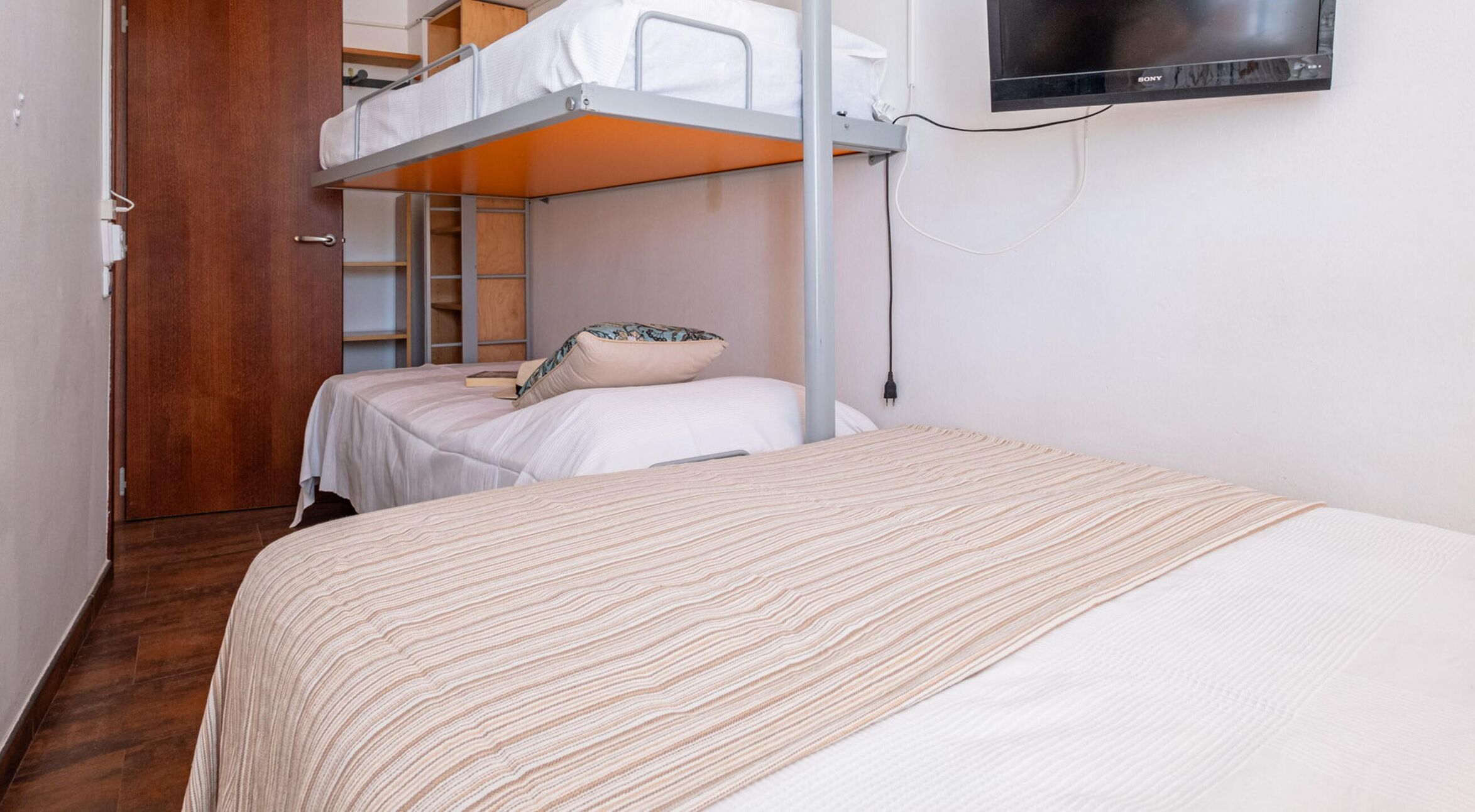 A bunk bed room with a television mounted on the wall.
