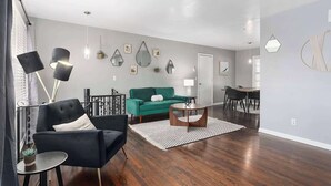 Un salon moderne avec un fauteuil noir, un canapé vert et un coin repas comprenant une table et des chaises.