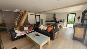 A spacious living area with a sofa set, a coffee table, and a staircase leading to an upper level. - Modern Forest-Edge Home for 10 with WiFi, Close to Beach & Shops (Saint-Jean-de-Monts)