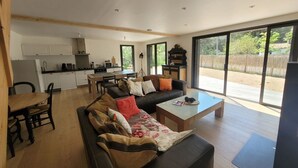 A modern living space with a sofa, coffee table, and dining area. - Modern Forest-Edge Home for 10 with WiFi, Close to Beach & Shops (Saint-Jean-de-Monts)
