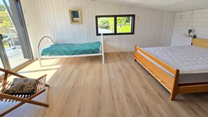 A room with a bed, a chair, a window, and a door. - Modern Forest-Edge Home for 10 with WiFi, Close to Beach & Shops (Saint-Jean-de-Monts)