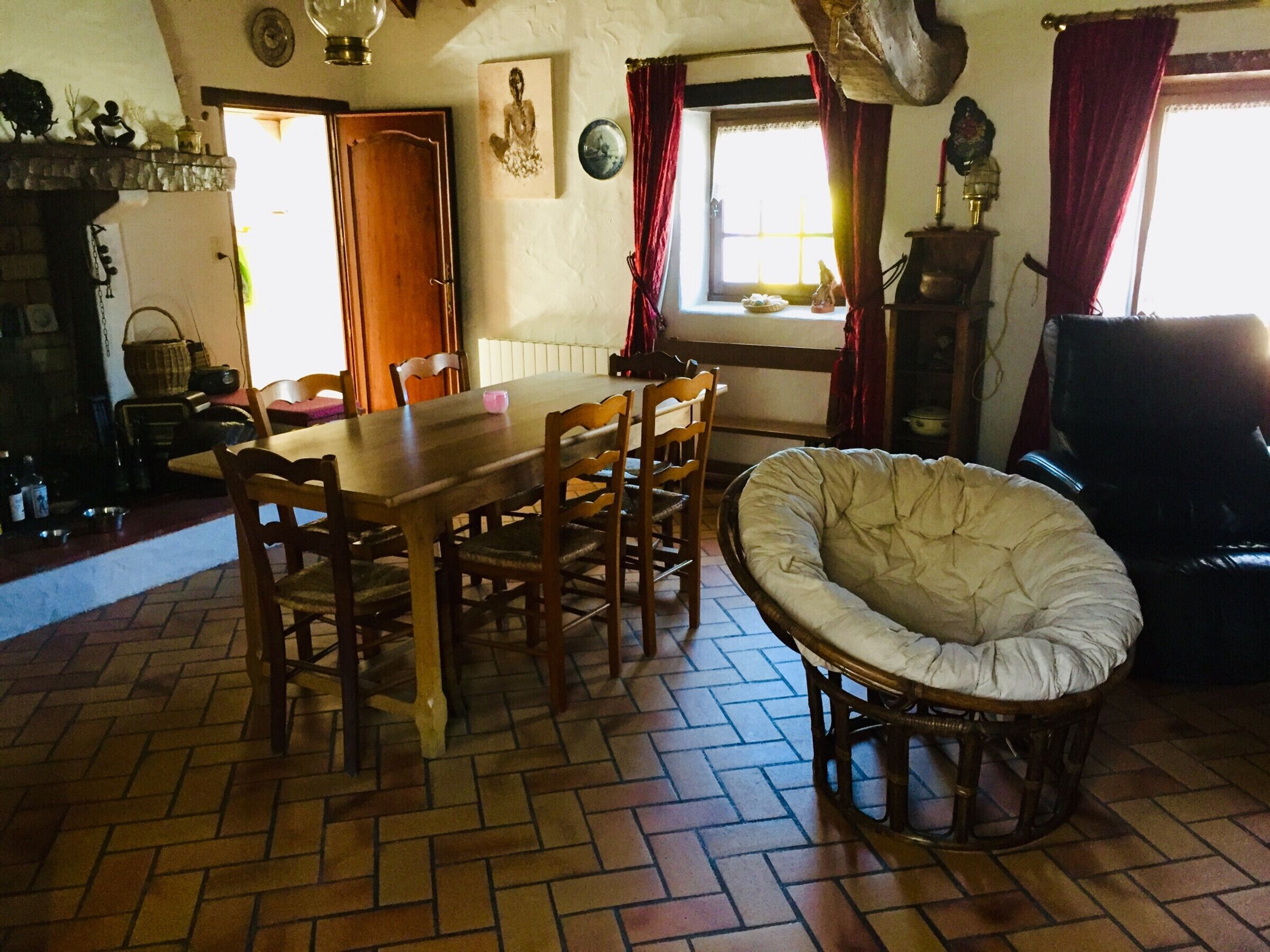 A dining area with a wooden table and chairs, a cushioned bench, and a brick floor.