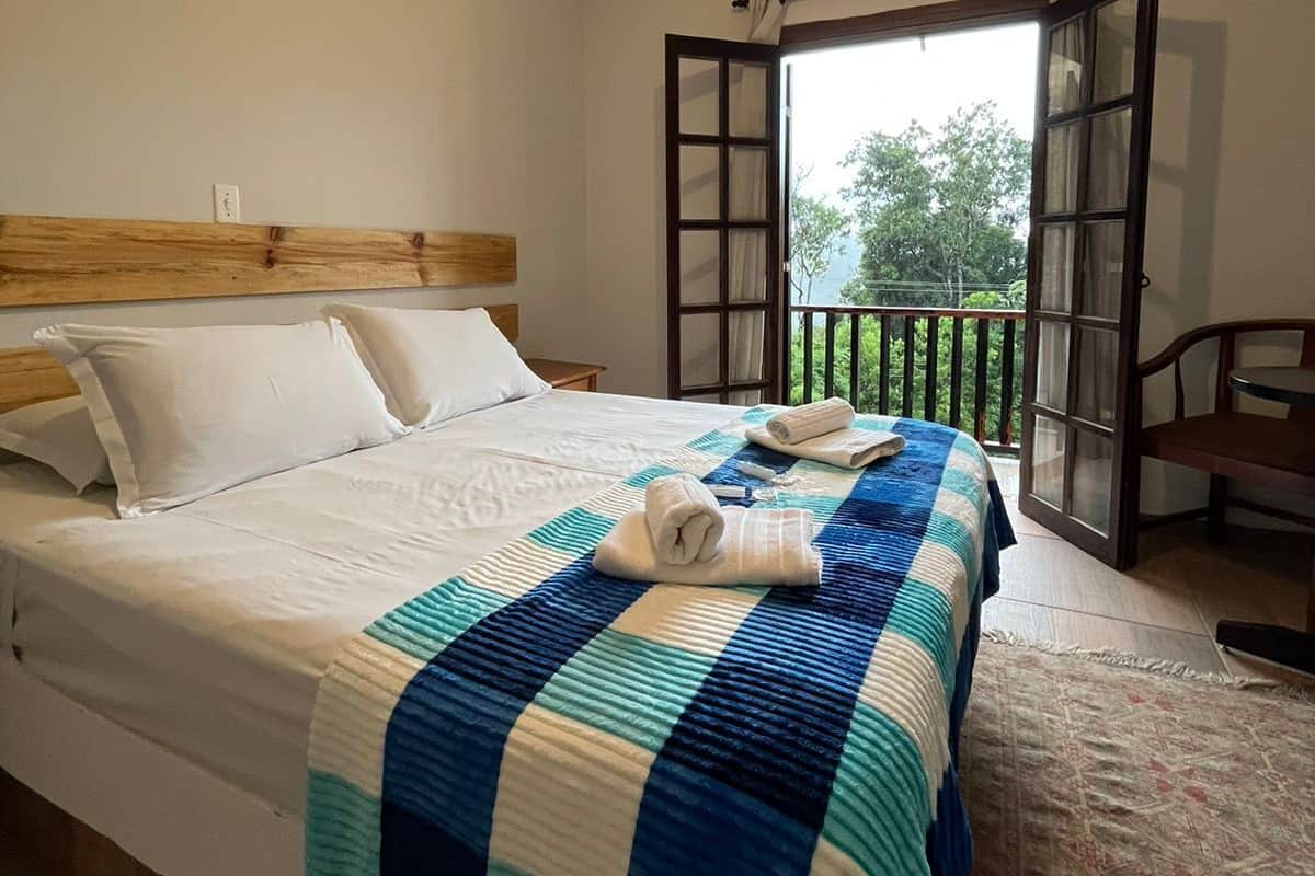 A bedroom with a bed, a wooden headboard, a window with a view, and a balcony.