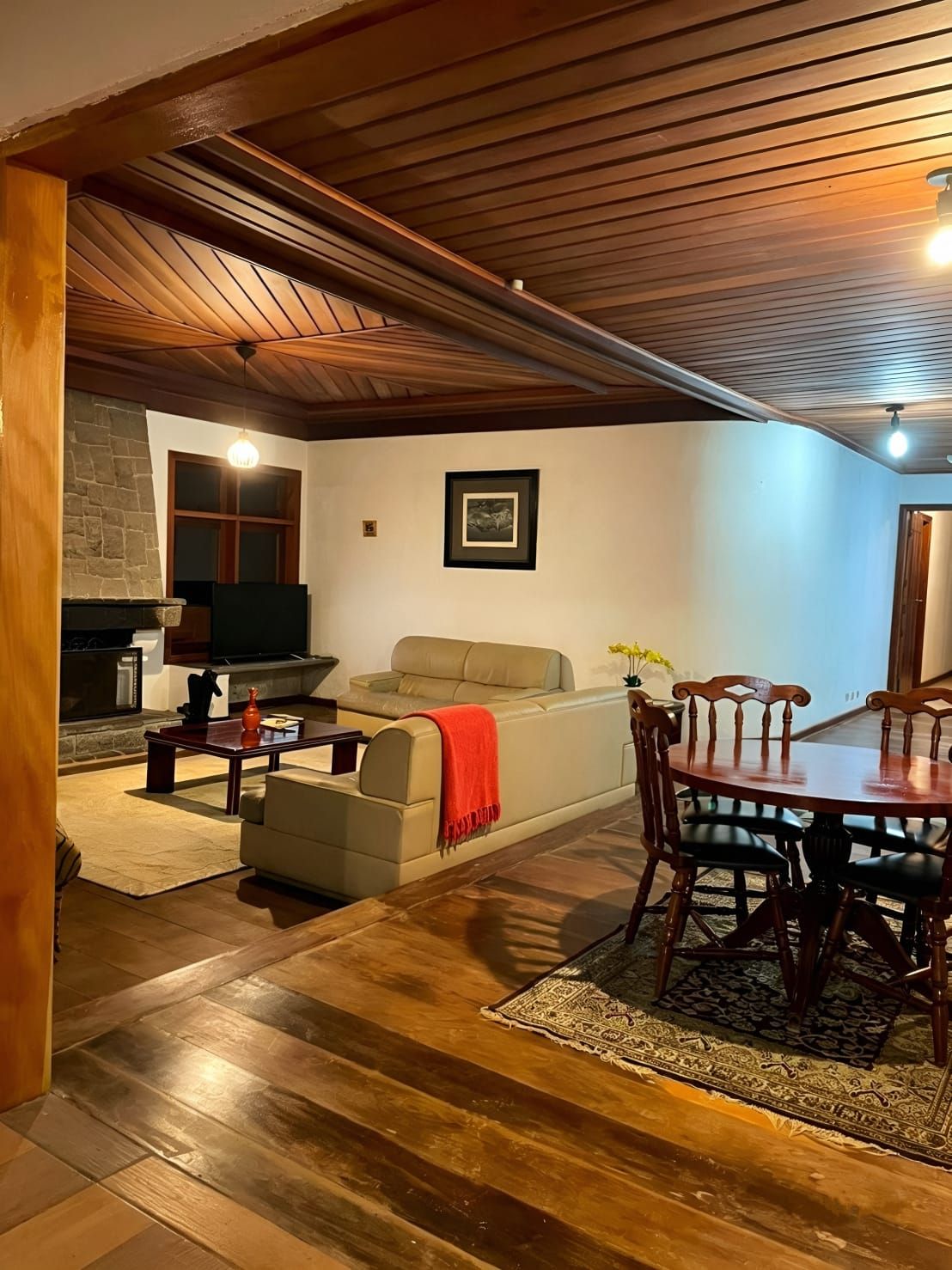 Uma sala de estar aconchegante com lareira, um sofá, uma mesa de jantar com cadeiras e uma parede de pedra.