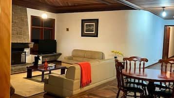 Ein gemütliches Wohnzimmer mit Kamin, einer Couch, einem Esstisch mit Stühlen und einer Steinwand.