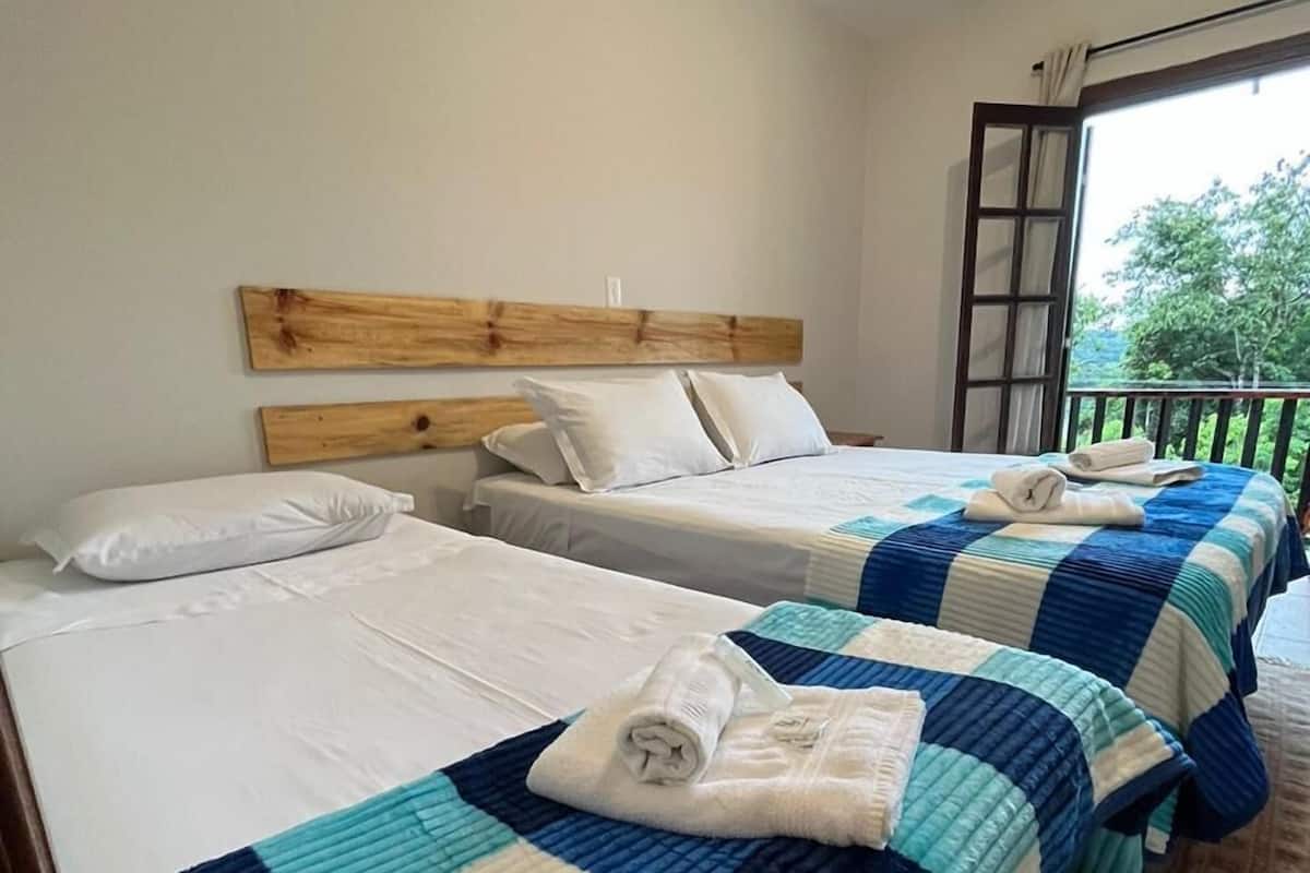 A hotel room with two beds, each with a blue and white quilt, white bedding, and a wooden headboard.