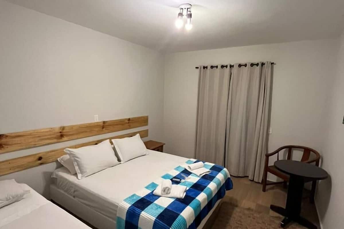 A hotel room with two beds, a wooden headboard, a small table, and a chair.