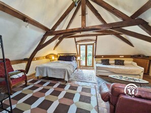 Une chambre confortable située dans les combles, avec un plafond en pente, un lit, un canapé et un tapis à motifs.