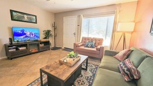 A living room with a television, a sofa, a coffee table, and a door.
