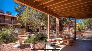 An outdoor patio area with a barbecue grill, seating, and a view of a building with balconies.