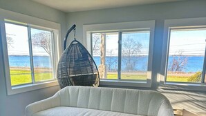 Una sala de estar moderna con un sofá blanco, ventanas amplias con vistas al exterior y una silla colgante.