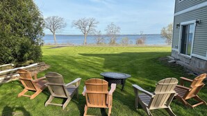 Un patio con sillas Adirondack y una mesa, con vista a un lago.