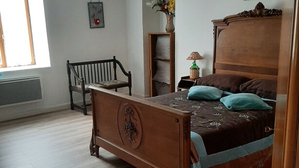 A bedroom with a wooden bed, a bench, a dresser, a lamp, and a window. - Gîte de Kerezenn (Fougerolles-Saint-Valbert)